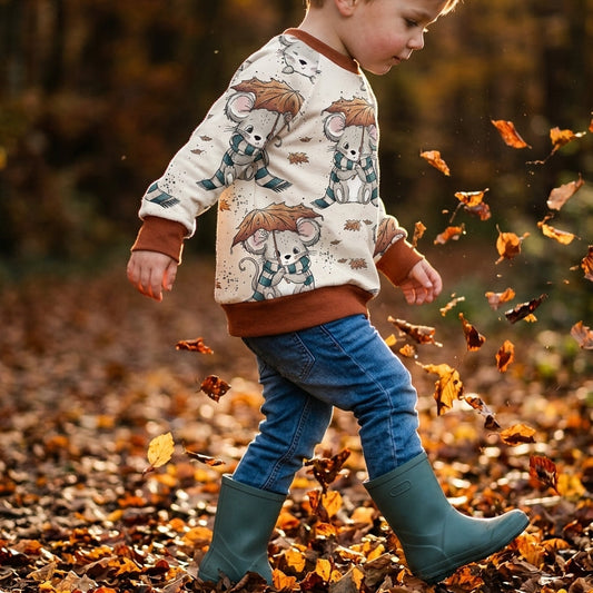 Junge im Kinderpullover mit Mäuse-Motiv beim Spielen im Herbstlaub